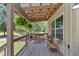 Covered porch with a wooden deck and comfortable seating for relaxing and enjoying the view at 12080 Se Sunset Harbor Rd, Weirsdale, FL 32195