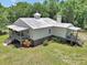 Secluded home with a metal roof, charming porch, and steps leading to the landscaped yard at 12080 Se Sunset Harbor Rd, Weirsdale, FL 32195