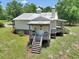 Rear exterior featuring steps leading to the porch and a well-maintained yard at 12080 Se Sunset Harbor Rd, Weirsdale, FL 32195
