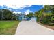 Two-story blue home with a long driveway and detached garage surrounded by lush trees and blue sky at 12690 Ne Highway 315, Fort Mc Coy, FL 32134