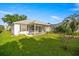 The backyard boasts an enclosed patio, lush green lawn, and mature landscaping at 1308 La Estrellita Way, The Villages, FL 32162