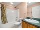 This bathroom features a shower-tub combo with floral curtains, a white toilet, and a vanity with a green countertop at 1308 La Estrellita Way, The Villages, FL 32162
