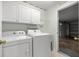 Laundry room featuring white appliances, storage cabinets, and access to garage at 1308 La Estrellita Way, The Villages, FL 32162