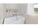 A modern white freestanding bathtub in the bathroom with marble walls and gold fixtures at 13663 Sw 66Th St, Ocala, FL 34481