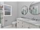 Bathroom featuring double sinks, marble countertops, and round mirrors at 14550 Sw 61St Ct, Ocala, FL 34473