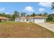 A single-story home featuring a neutral gray paint scheme, brown roof, long driveway, and an attached two-car garage at 14550 Sw 61St Ct, Ocala, FL 34473