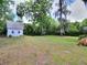 Expansive backyard featuring a shed with a metal roof, surrounded by mature trees and lush greenery at 1610 Se 22Nd Ave, Ocala, FL 34471