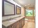 Bathroom with double sinks, framed mirrors, tiled floor, and a glass enclosed shower at 1610 Se 22Nd Ave, Ocala, FL 34471