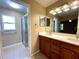 Bathroom with dual sinks, wood cabinets, a walk-in shower, tile flooring, and contemporary lighting fixtures at 16405 Sw 14Th Avenue Rd, Ocala, FL 34473