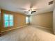 Spacious carpeted bedroom features neutral paint, a ceiling fan, and plantation shutters on two large windows at 16405 Sw 14Th Avenue Rd, Ocala, FL 34473