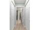 Hallway with wood-look floors, white doors, and a view into the bathroom at 19028 Sw 101 Pl, Dunnellon, FL 34432