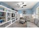 Comfortable living room with custom shelving, a ceiling fan, and a serene blue color scheme at 19370 Saint Benedict Dr, Dunnellon, FL 34432