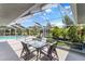 Outdoor patio area with a dining set surrounded by lush landscaping and a pool at 19942 Sw 96Th Pl, Dunnellon, FL 34432