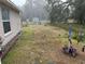 Backyard view in the rain with grass, utility shed, and chain link fence at 27 Cedar Tree Ter, Ocala, FL 34472