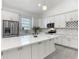 Well-lit kitchen with stainless appliances, quartz countertops, stylish backsplash, and spacious island at 4370 County Road 121D, Wildwood, FL 34785