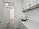 Charming laundry room has white shaker cabinets, gray wood floors and a stainless steel sink at 4370 County Road 121D, Wildwood, FL 34785