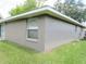 Side exterior view of a single story home with a gray stucco finish and white trim on a well maintained lawn at 5083 Se 26Th St, Ocala, FL 34480