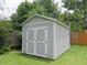 A well-kept grey shed stands in a green yard surrounded by mature trees at 5083 Se 26Th St, Ocala, FL 34480