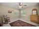 Neutral bedroom with a ceiling fan, rocking chair, and natural light from two windows at 5174 Se 41St Ave, Ocala, FL 34480