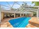 Bright in-ground screened pool boasts stone-look patio, water feature and access to covered lanai at 5174 Se 41St Ave, Ocala, FL 34480