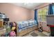 Modest bedroom with daybed, window with curtains, ceiling fan, and storage drawers below daybed at 6070 Se 39Th Ave, Ocala, FL 34480