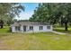 Charming one-story home with white exterior, well-maintained lawn, and mature trees on a sunny day at 6350 Nw 135Th Ave, Morriston, FL 32668
