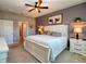 Bedroom featuring a ceiling fan, ensuite bath entrance, cow themed art, and carpet flooring at 6405 Sw 88Th Loop, Ocala, FL 34476