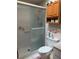 Modest bathroom featuring a glass shower, toilet, medicine cabinet and floral wallpaper at 7251 Sw 115Th Pl, Ocala, FL 34476