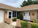 Inviting front entrance with a white door, decorative wall art, and lush landscaping enhancing the curb appeal at 7251 Sw 115Th Pl, Ocala, FL 34476