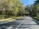 Inviting neighborhood road with lush landscaping and mature trees, leading to a welcoming community entrance at 7637 Sw 180Th Cir, Dunnellon, FL 34432