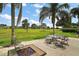 Backyard view of the patio with outdoor furniture and a fire pit, surrounded by a lush lawn and landscaping at 8772 Se 130Th Loop, Summerfield, FL 34491