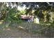Single-story home nestled amongst mature trees and a rusty metal roof, surrounded by greenery at 1050 E Highway 329, Citra, FL 32113