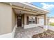 Covered front porch featuring a brick-paved walkway, wood door, and sconce lighting at 10562 Sw 96Th Lane Rd, Ocala, FL 34481
