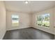 Bright bedroom with wood-look tile flooring and two windows offering natural light and serene views at 10910 Sw 41St Ave, Ocala, FL 34476