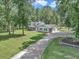 Exterior view of home with a metal roof, manicured lawn, and long driveway at 12677 Se 53Rd Terrace Rd, Belleview, FL 34420