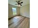 Bright bedroom with wood flooring, ceiling fan, and a window overlooking the backyard at 13319 Sw 106Th Pl, Dunnellon, FL 34432