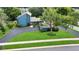 Aerial view of a modern blue home featuring a well-manicured lawn, driveway, and mature landscaping at 2922 Cocovia Way, Leesburg, FL 34748
