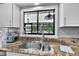 Granite countertop and stainless steel sink with a window overlooking the lush greenery outside at 2922 Cocovia Way, Leesburg, FL 34748