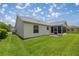 Backyard view showing the home's exterior with screen enclosed lanai and well-maintained lawn at 3024 Burbank Ln, The Villages, FL 32162