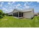 Backyard view featuring a screened-in lanai and lush lawn at 3024 Burbank Ln, The Villages, FL 32162