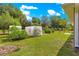 Lush backyard featuring green grass, vegetable garden, trees, and clear skies at 3445 Se 139Th Ln, Summerfield, FL 34491
