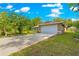 Home featuring a long driveway leading to a two-car garage and a well-manicured lawn at 3445 Se 139Th Ln, Summerfield, FL 34491