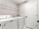 Bright laundry room with washer, dryer, wire shelving, and white paneled door at 3445 Se 139Th Ln, Summerfield, FL 34491