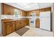 Kitchen featuring wood cabinets, white appliances, tile flooring and good lighting at 4467 Sw Channel Heights Ct, Dunnellon, FL 34431