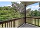 Charming balcony view with wooden railing overlooking lush greenery and mature trees on a partially sunny day at 4673 Se 115Th St, Belleview, FL 34420