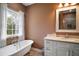 Elegant bathroom with a freestanding tub, granite countertop, and decorative mirror reflecting glass enclosed shower at 4673 Se 115Th St, Belleview, FL 34420