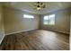 An airy bedroom featuring a tray ceiling, ceiling fan, and wood-look flooring at 4940 Sw 63Rd Loop, Ocala, FL 34474