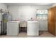 Functional laundry room with washer, dryer, sink, water heater, and storage cabinet, all in a clean, well-lit space at 5005 Ne 22Nd Ave, Ocala, FL 34479