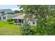 Rear view of home featuring screened in porch, large trees, and well-maintained lawn at 5007 Kelso St, Leesburg, FL 34748