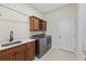 Well-equipped laundry room with custom cabinets, a utility sink, and modern stainless steel washer and dryer at 5092 Ne 81St Blvd, Wildwood, FL 34785